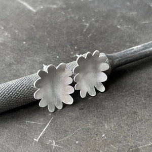 Large sterling silver flower abstract studs leaning  on steel tool